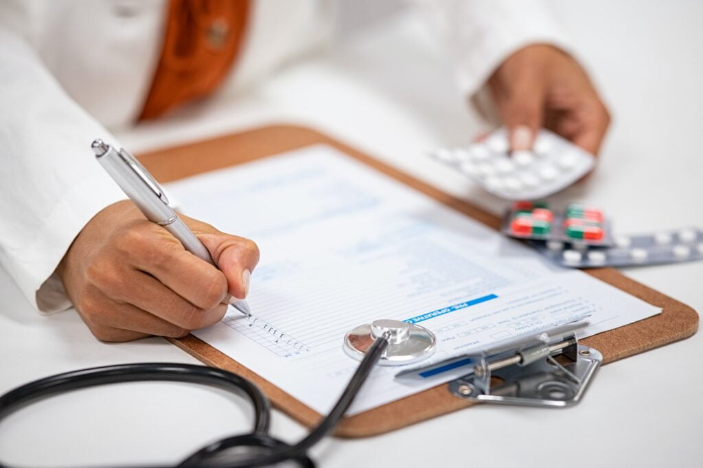 Doctor writing and checking medical prescription